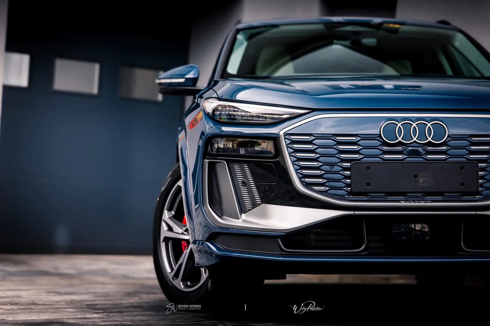 Detail přední masky a světlometu modrého Audi Q6 e-tron.