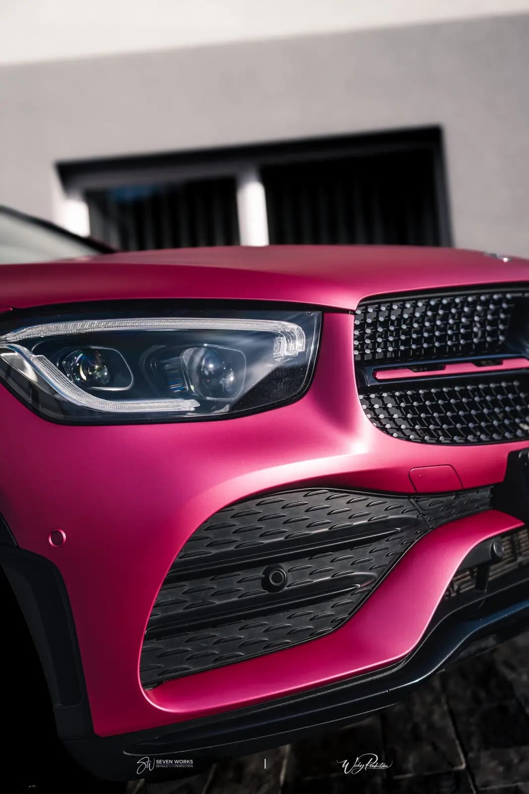 Detail přední masky a světlometu růžově polepeného Mercedesu-Benz.