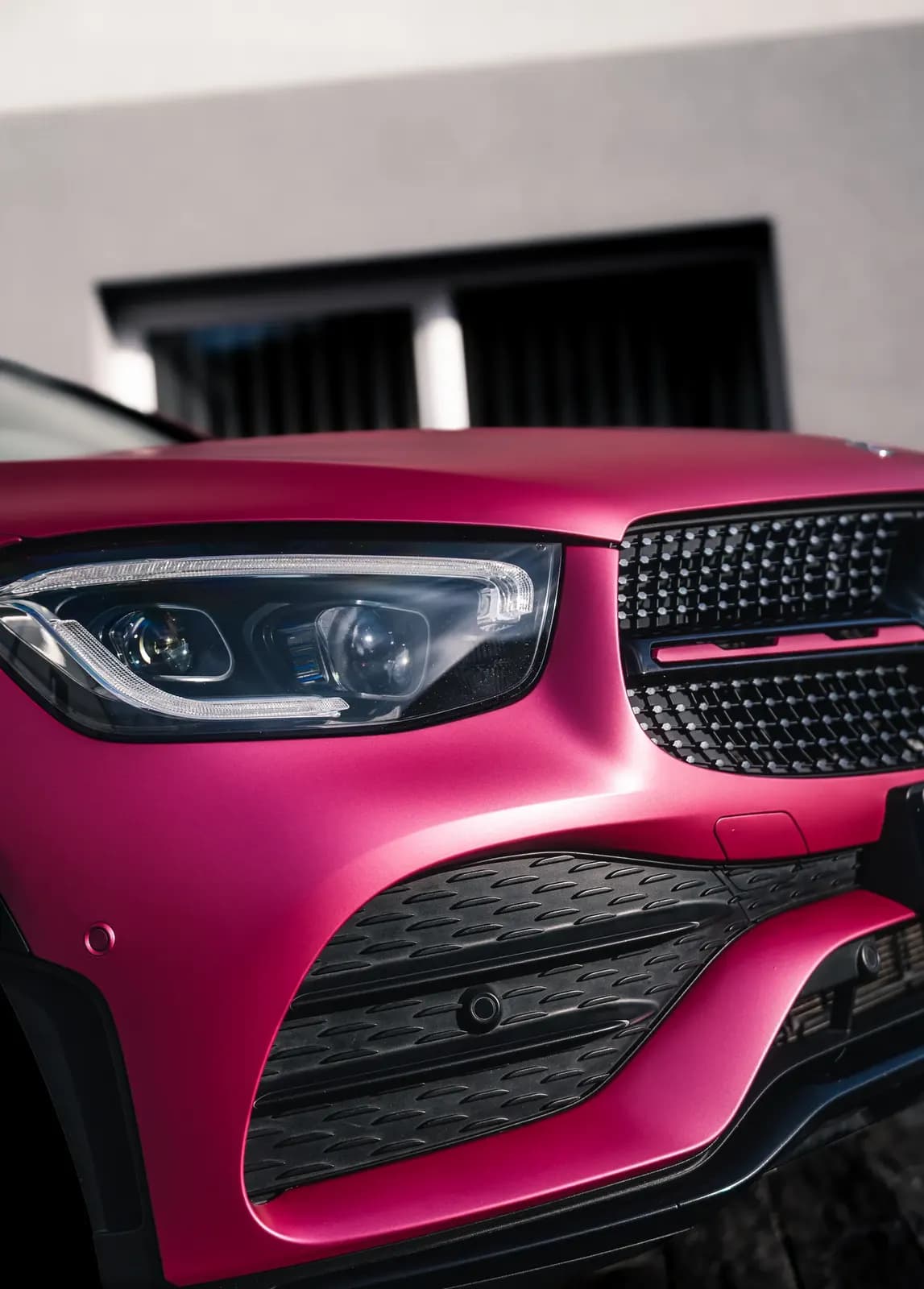 Detail přední masky a nárazníku vozu v matném růžovém polepu wrap.