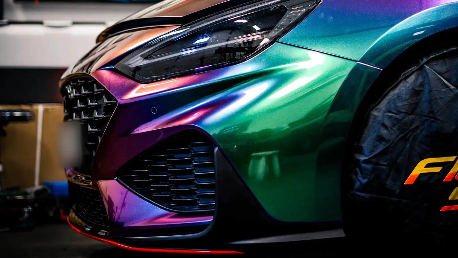 Přední část sportovního hatchbacku potažená duhově zbarvenou (chameleon) polepovou fólií.