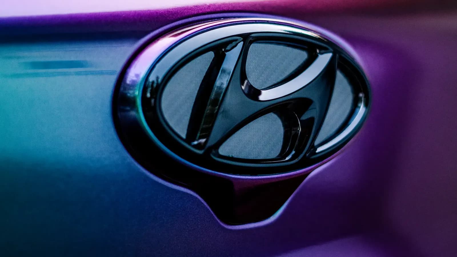 Detail loga Hyundai na karoserii potažené duhově zbarvenou polepovou fólií.