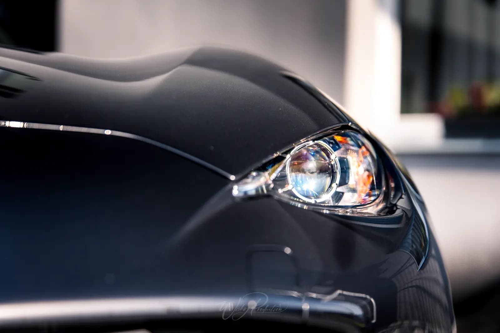 Detail světlometu a hrany kapoty Mazdy MX-5 v protisvětle.
