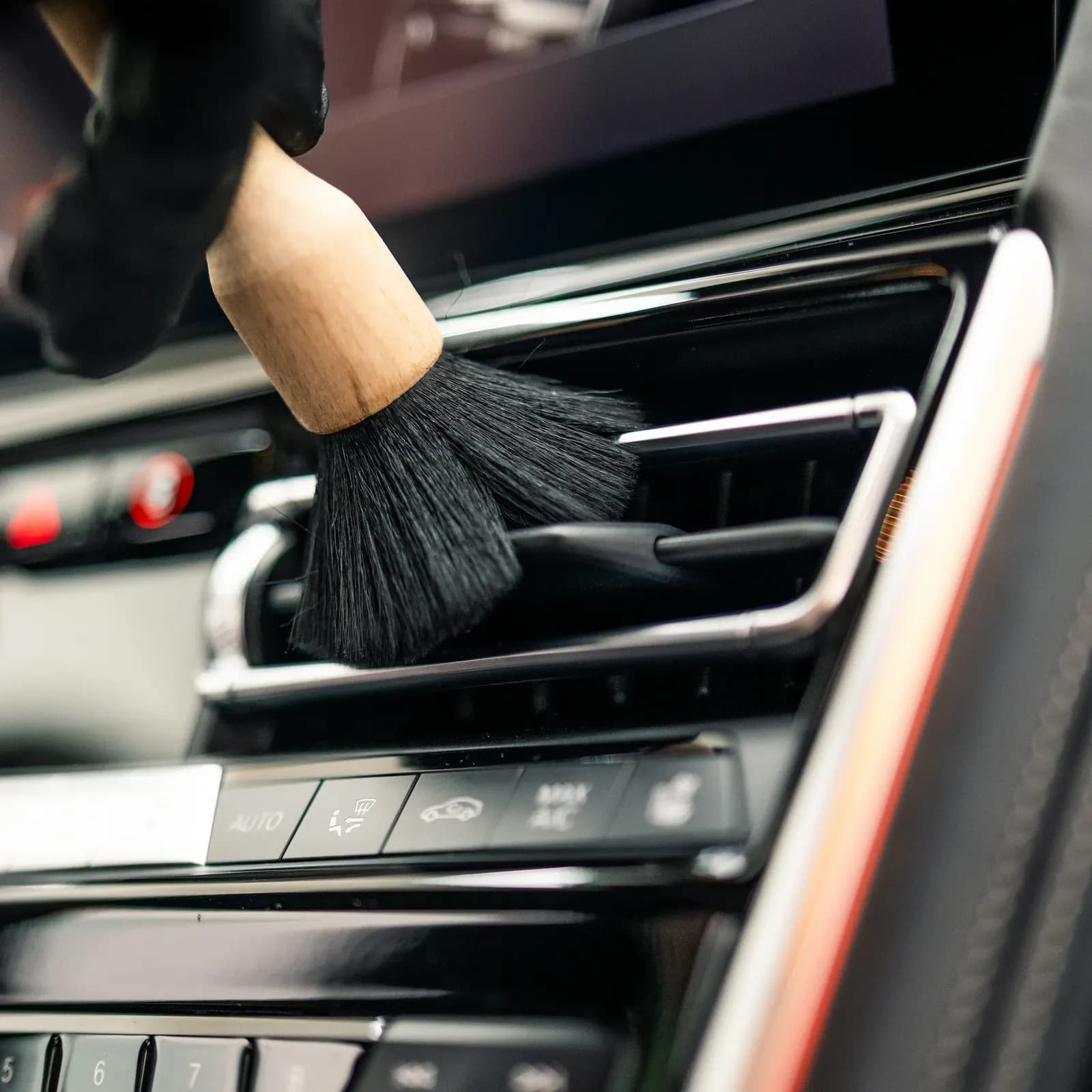 Čištění výdechu ventilace interiéru vozu kulatým detailingovým kartáčkem.