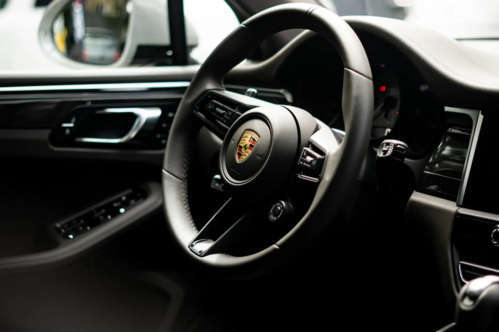 Detail volantu se znakem Porsche v interiéru vozu, statický záběr.