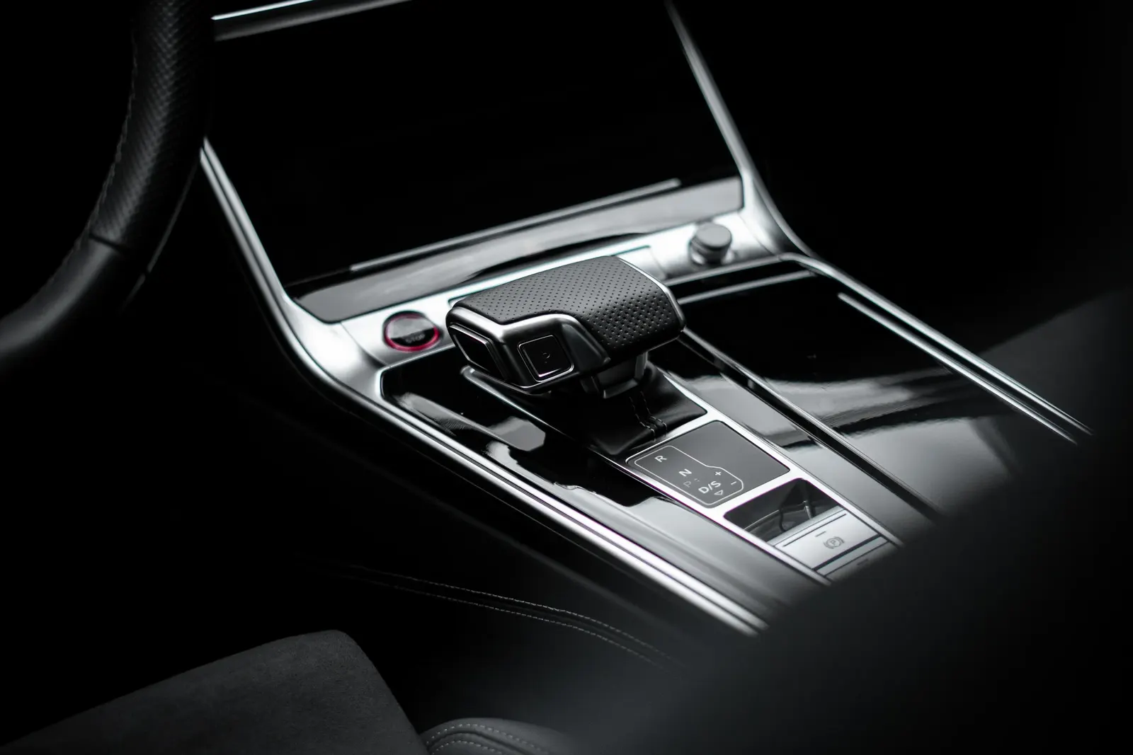 Detail řadicí páky a lesklého středového panelu v interiéru vozu Audi.