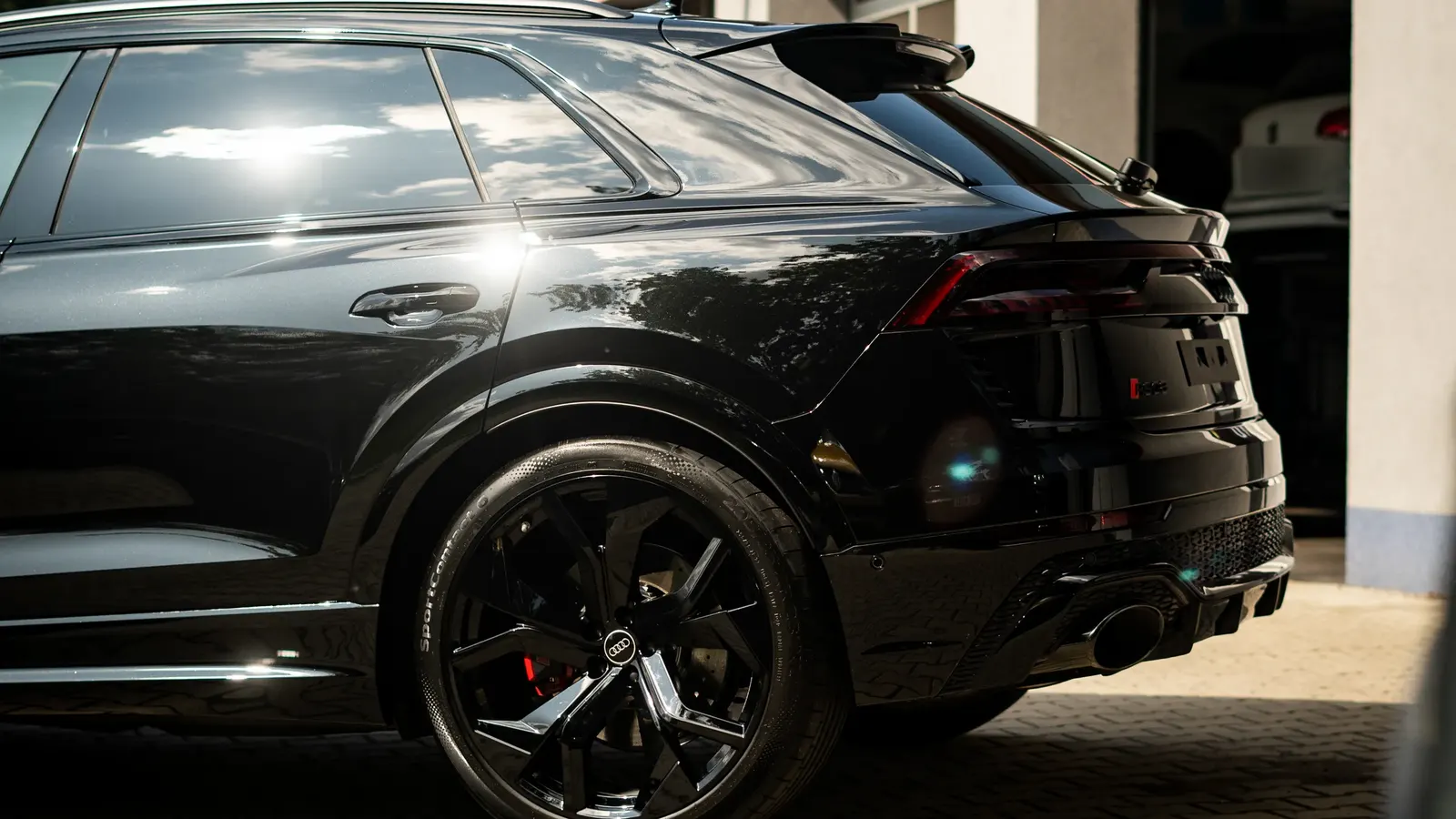 Side and rear view of a black sports SUV parked in front of a house.