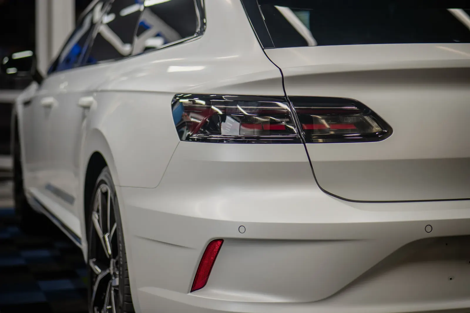 Detail zadního světla bílého vozu v interiéru showroomu.