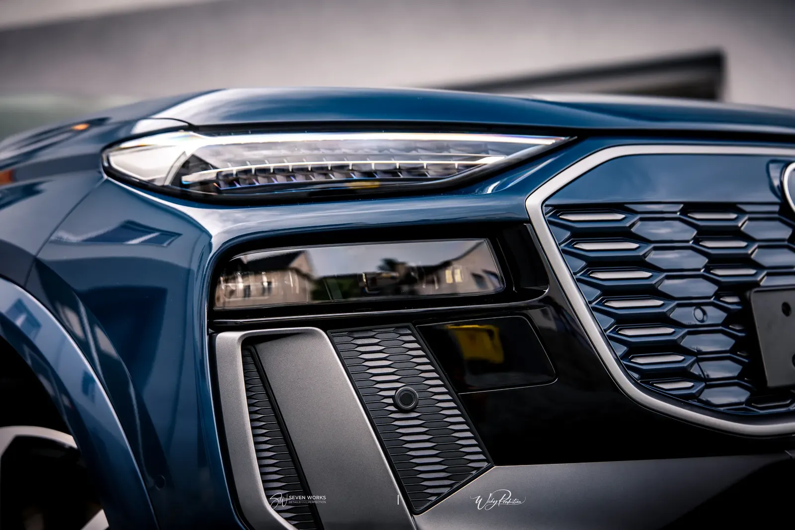 Makro detail světla a masky chladiče tmavě modrého Audi SUV.