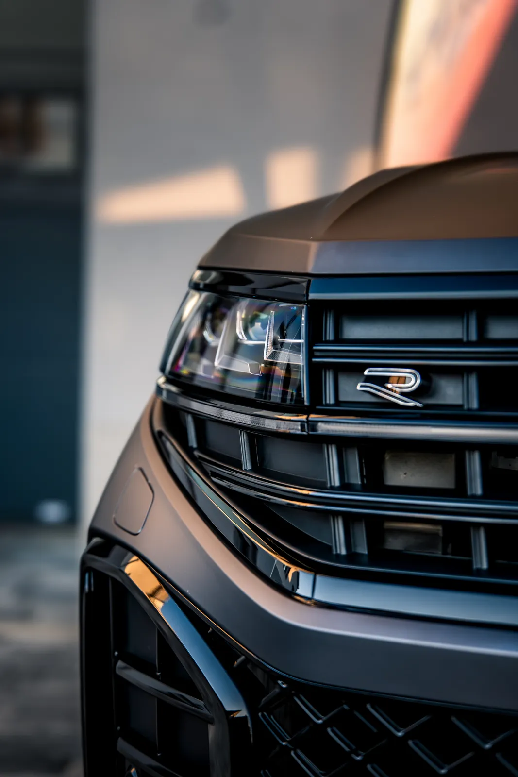 Detail předního světlometu, masky s označením R a nárazníku Volkswagenu Touareg v matné šedé fólii.