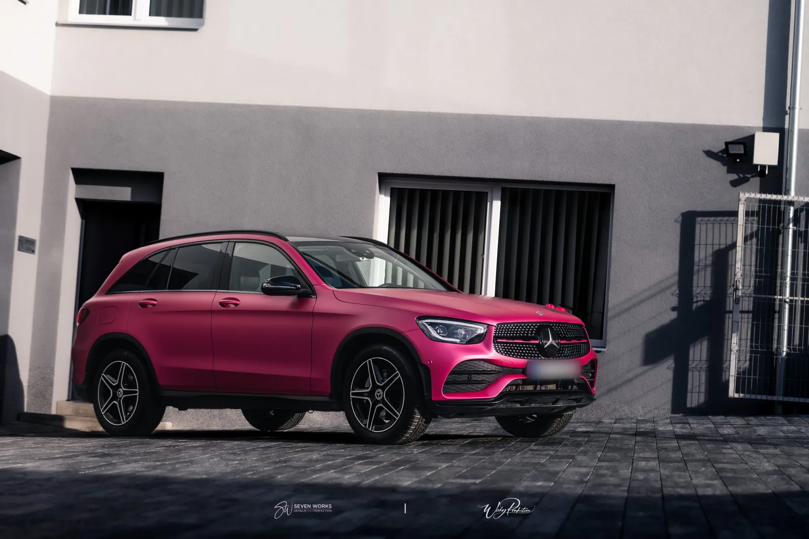 Růžově polepené SUV Mercedes-Benz z boku před šedou fasádou provozovny.